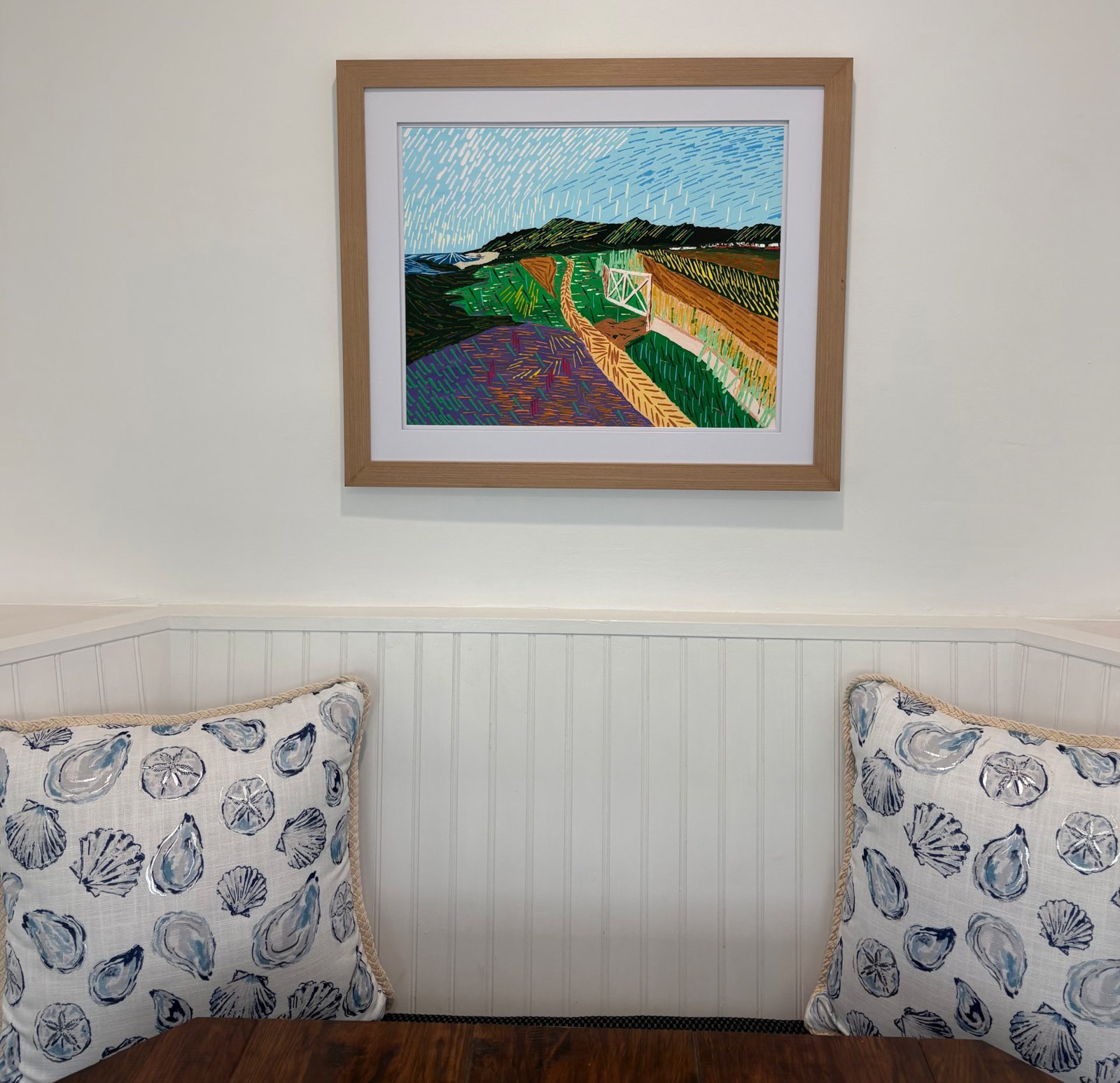 “Generations” print framed in natural wood with a white mat, hanging above a bench